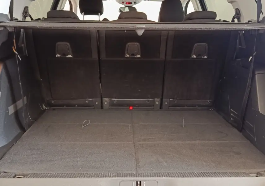 Vue intérieure du coffre spacieux du Peugeot 5008 gris foncé, avec sièges arrière rabattus et tablette de séparation visible.