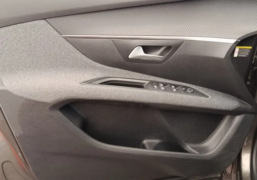 Gros plan sur la porte avant droite grise du Peugeot 5008 2020, avec commandes électriques et habillage tissu.