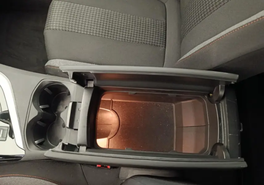 Vue plongeante sur la console centrale ouverte du Peugeot 5008 gris foncé, montrant le rangement intérieur et porte-gobelets.