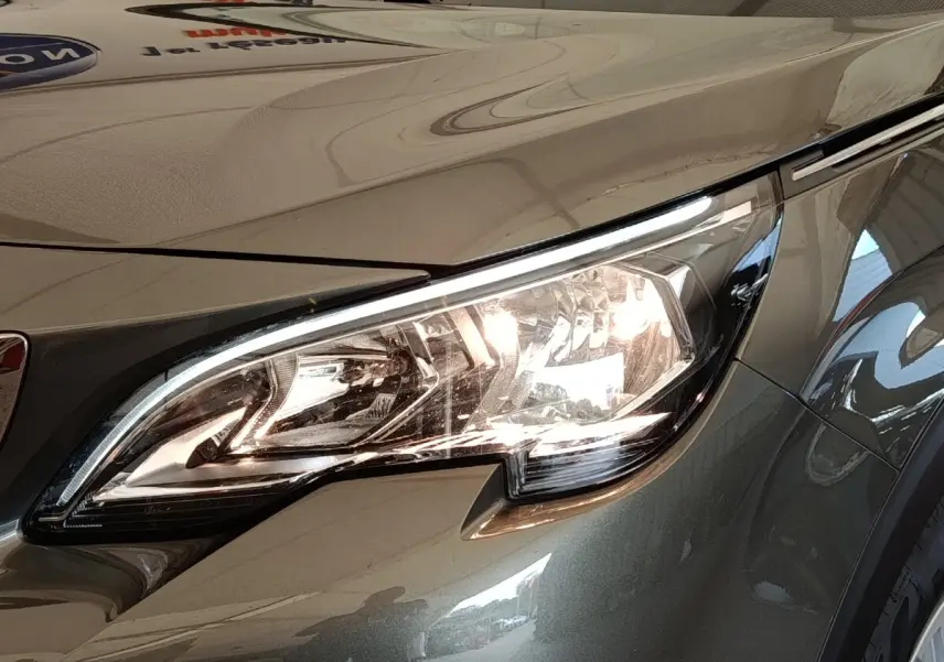 Gros plan sur le phare avant droit du Peugeot 5008 gris foncé, mettant en valeur son design moderne et lumineux.