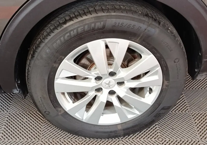 Gros plan sur la roue avant droite d’un Peugeot 5008 gris foncé, avec jante alliage et pneu Michelin.