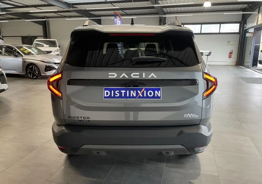 Vue arrière d'un Dacia Bigster gris schiste avec feux LED en forme de C et logo Dacia lumineux.