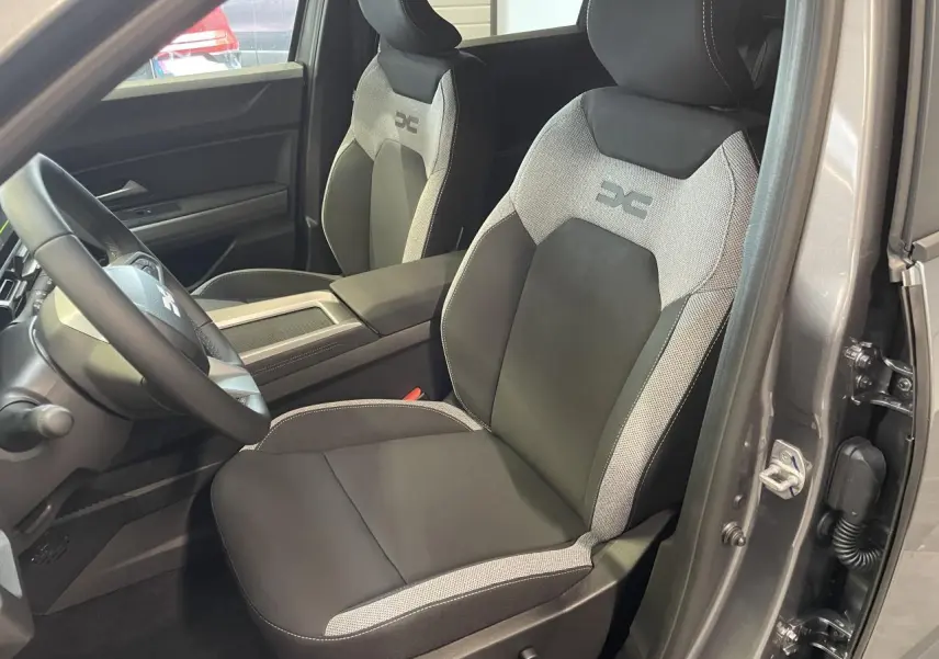 Vue intérieure côté conducteur du Dacia Bigster gris schiste, mettant en valeur la sellerie Journey bicolore avec logo brodé.