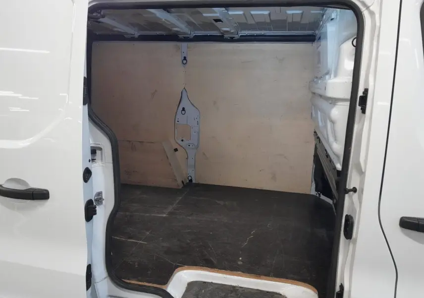 Vue intérieure de la partie chargement du Renault Trafic Fourgon blanc minéral, porte latérale droite ouverte.