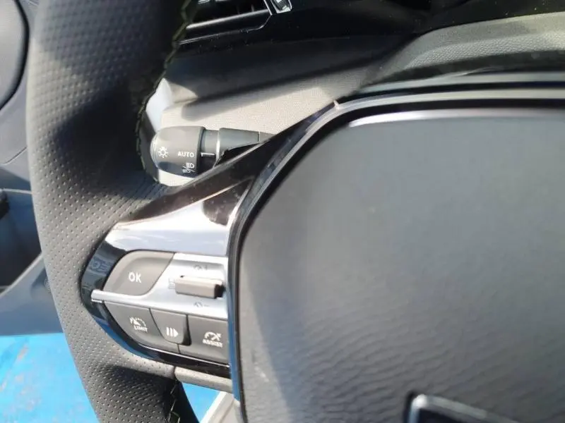Gros plan sur le volant multifonction noir de la Peugeot 308 Hybrid 2026, montrant les commandes côté gauche.