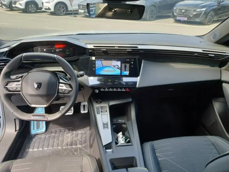 Vue intérieure avant de la Peugeot 308 Hybrid 2026 montrant le volant compact, l'écran tactile central et les commandes modernes.