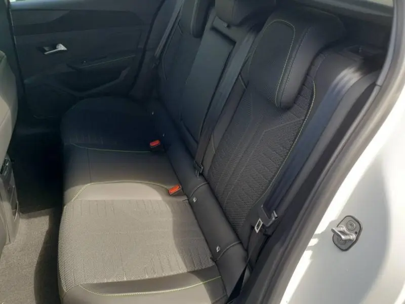 Vue intérieure côté droit des sièges arrière noirs avec surpiqûres vertes du Peugeot 308 Hybrid blanc Okénite.