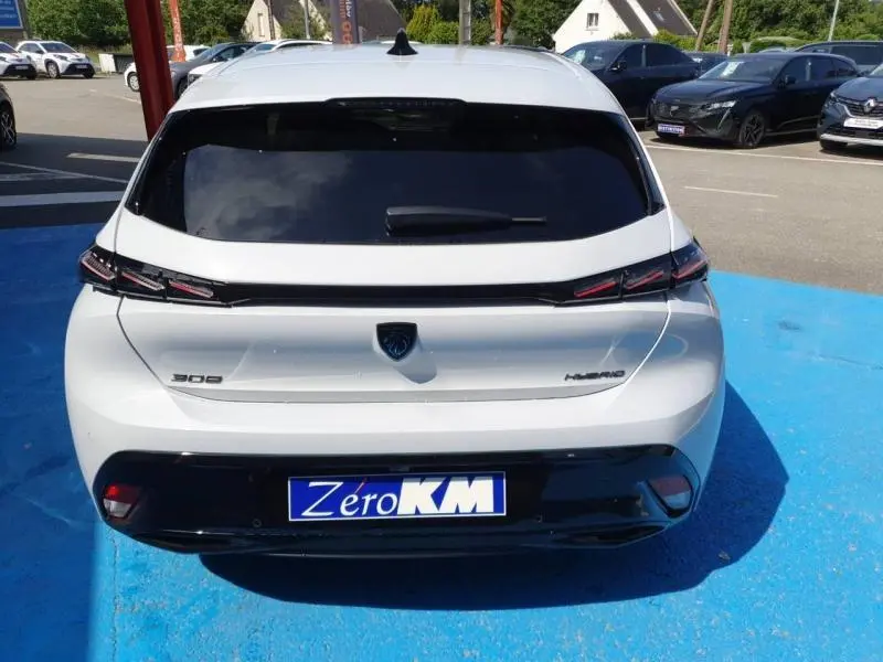 Vue arrière d'une Peugeot 308 blanche Okénite avec feux arrière LED et lunette arrière surteintée.