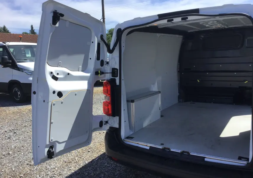 Vue arrière ouverte d'un Opel Vivaro blanc 2023, montrant l'espace de chargement vide et les portes battantes déployées.