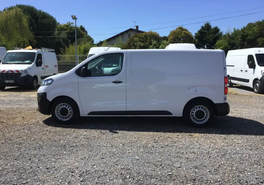 Profil côté gauche d'un utilitaire blanc Opel Vivaro 2023, version M 1.5 BlueHDi 120, sur un parking extérieur.