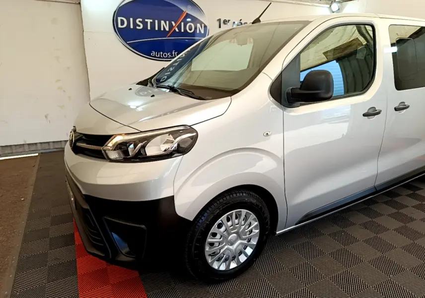 Vue 3/4 avant droit d'un Toyota Proace Verso gris clair avec pare-chocs noir et jantes acier en showroom.