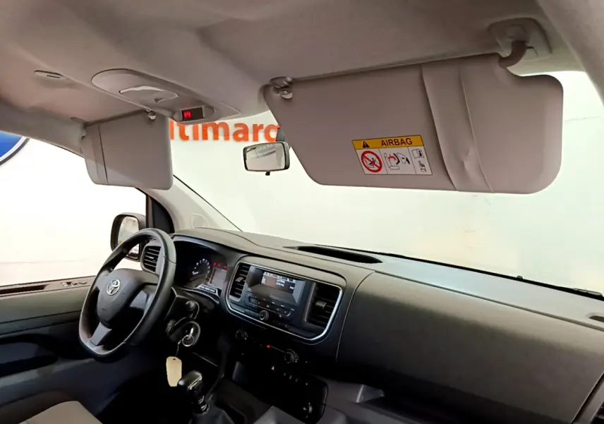 Vue intérieure côté conducteur du Toyota Proace Verso 2019, tableau de bord noir avec volant multifonctions et pare-soleil baissé.