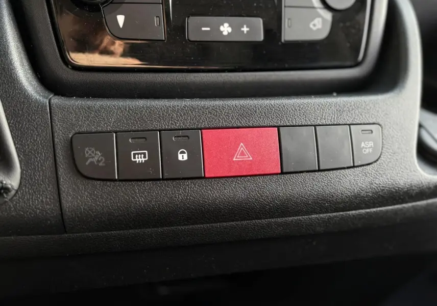 Gros plan sur la rangée de boutons noirs et rouge du tableau de bord de l’Opel Movano Fourgon 2024, intérieur noir.