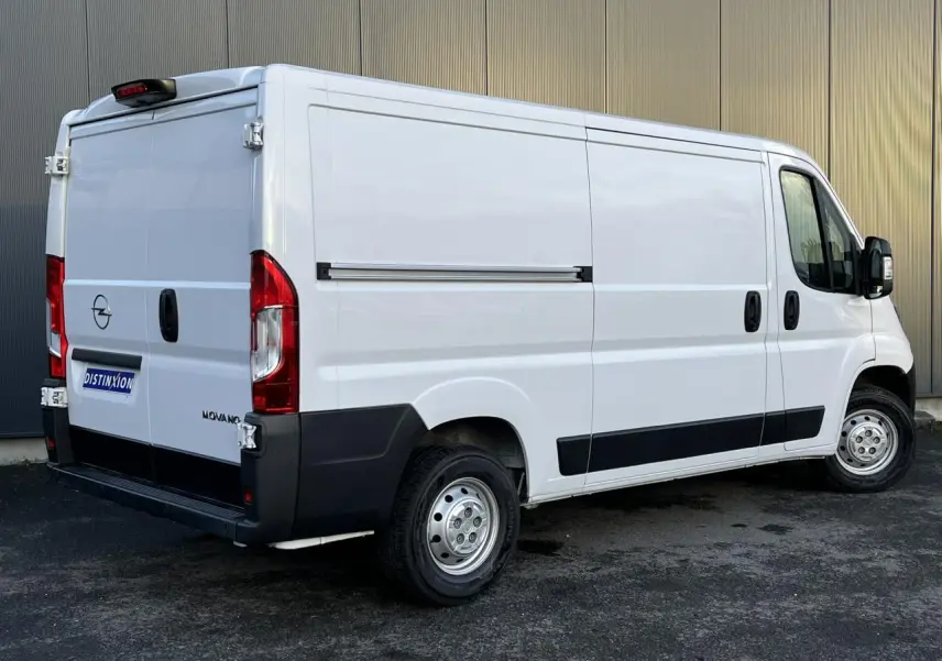 Vue 3/4 arrière droite d'un Opel Movano Fourgon blanc avec porte latérale coulissante et protections noires.