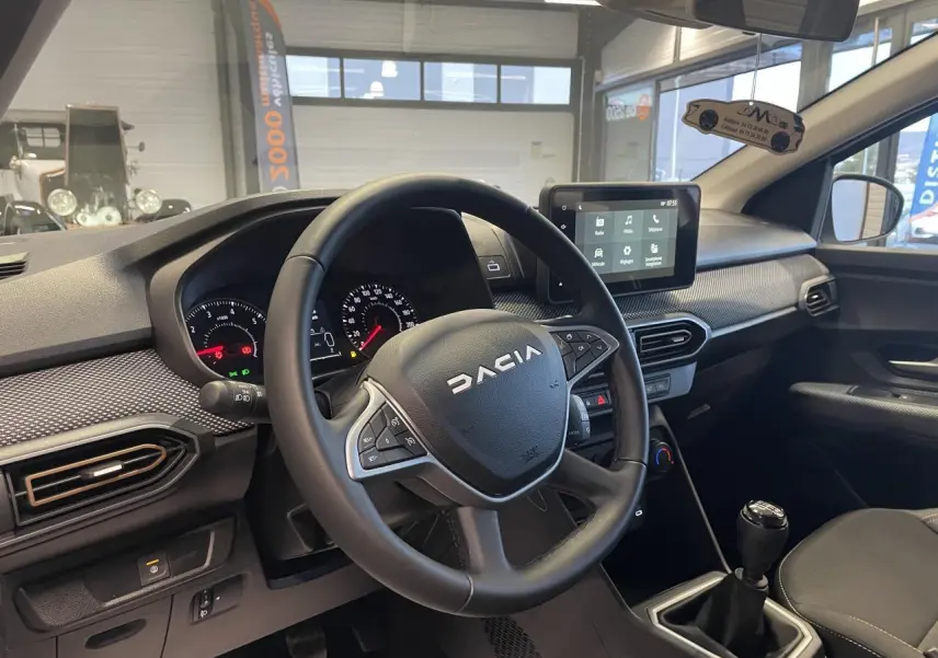 Vue intérieure côté conducteur du tableau de bord et volant noir de la Dacia Sandero TCe 90 Stepway 2025.