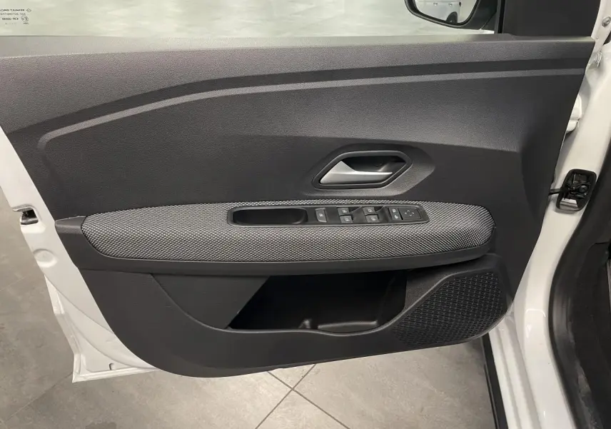 Vue côté gauche de la porte avant blanche du Dacia Sandero Stepway 2025 avec commandes de vitres et poignée grise.