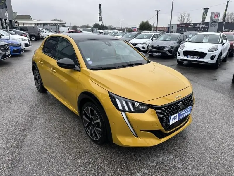 Peugeot 208 jaune vue 3/4 avant droit, avec calandre noire distinctive et feux LED en forme de griffes.