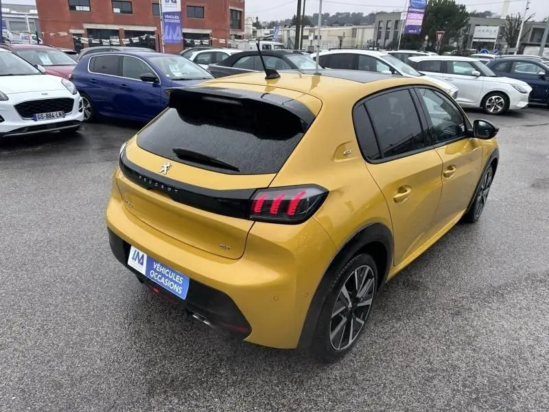 Vue 3/4 arrière droite d'une Peugeot 208 jaune 1.2 PureTech 130 GT 2021 avec feux arrière à griffes distinctifs.