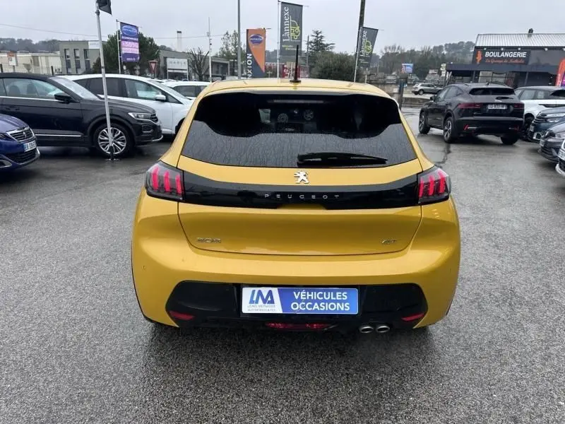 Vue arrière d'une Peugeot 208 jaune 1.2 PureTech 130 GT 2021 avec feux arrière à griffes et double sortie d'échappement.