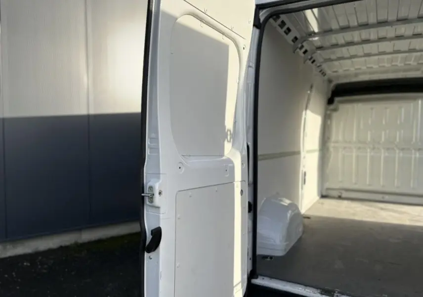 Vue intérieure de la porte latérale ouverte du fourgon blanc Opel Movano 2023, montrant l’espace de chargement vide.