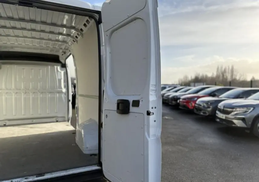 Vue arrière droite du fourgon blanc Opel Movano 2023 avec porte arrière ouverte montrant l’espace de chargement vide.