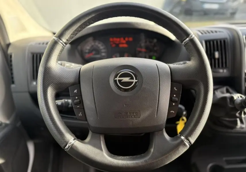 Volant noir de l'Opel Movano Fourgon 2.2 BlueHDi 140, vue frontale centrée sur les commandes au volant.