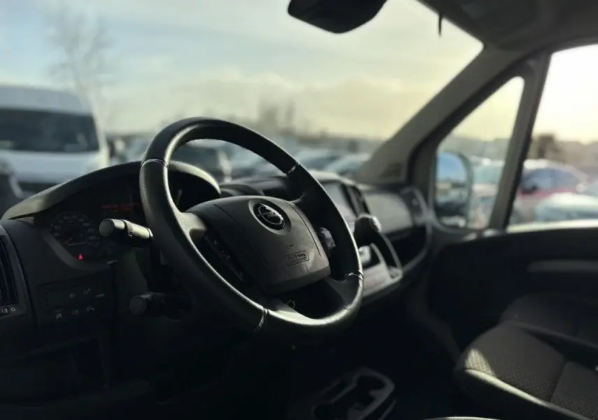 Vue intérieure du poste de conduite de l’Opel Movano Fourgon blanc, avec volant et tableau de bord en lumière naturelle.