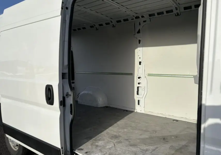Vue latérale droite du fourgon blanc Opel Movano 2023 avec porte coulissante ouverte montrant l’espace de chargement vide.