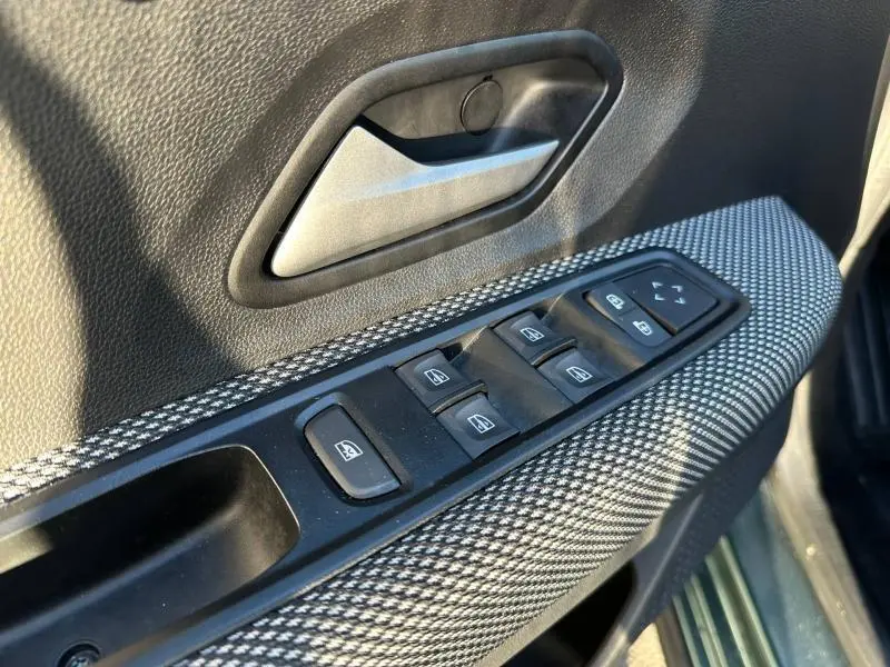 Gros plan sur la commande des vitres électriques côté conducteur avec tissu gris à motifs sur la portière intérieure.