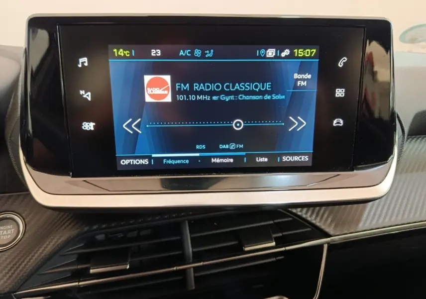 Écran tactile central de la Peugeot 208 électrique Active Business R 2022, affichant une radio FM sur tableau de bord noir.