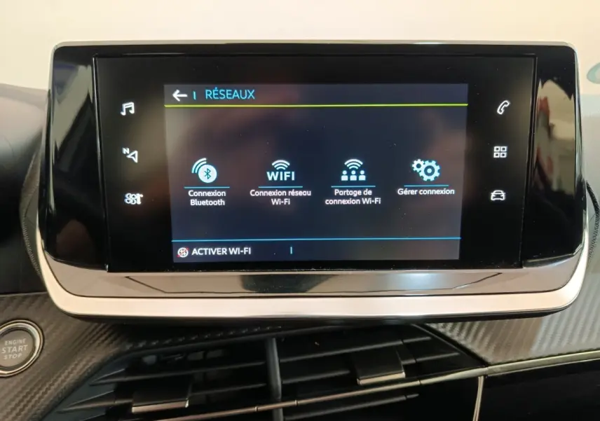 Écran tactile central de la Peugeot 208 électrique blanc, affichant les options de connexion réseau Wi-Fi et Bluetooth.