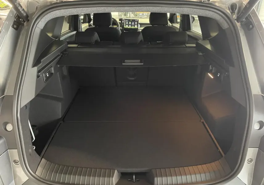 Coffre ouvert vu de l'arrière du Dacia Bigster gris schiste, montrant l'espace de chargement et la banquette arrière.