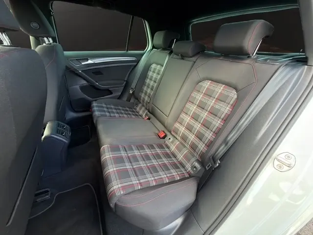 Vue intérieure arrière gauche de la Volkswagen Golf GTI Performance blanche, sièges arrière à motif tartan avec surpiqûres rouges.