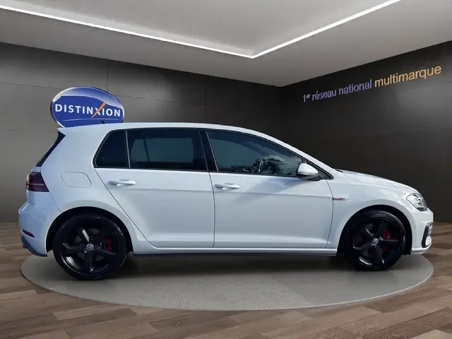 Volkswagen Golf GTI Performance blanche vue 3/4 avant droit avec jantes noires et détails rouges.