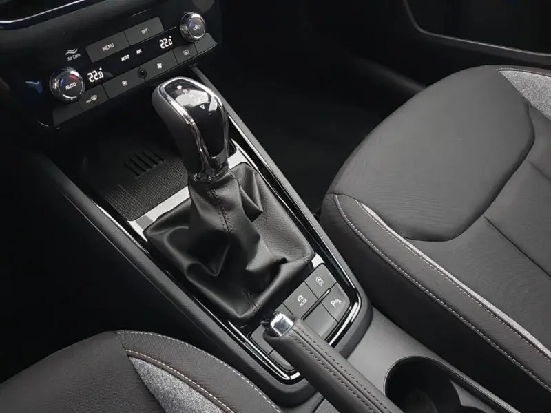 Gros plan sur la console centrale du Skoda Kamiq 2025, avec levier de vitesse automatique et sièges tissu noir/gris.