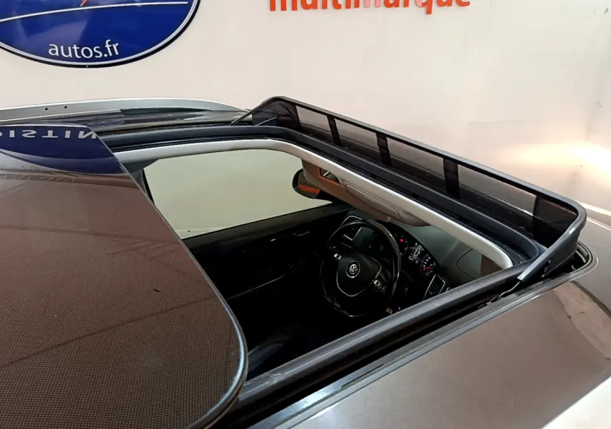 Vue plongeante sur le toit ouvrant ouvert d'un Volkswagen Sharan marron, dévoilant le volant et le tableau de bord intérieur.