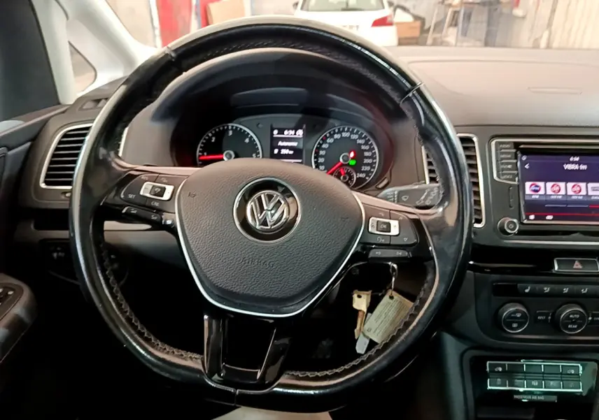 Vue rapprochée du volant cuir noir Volkswagen Sharan 2017 avec tableau de bord et écran tactile central visible