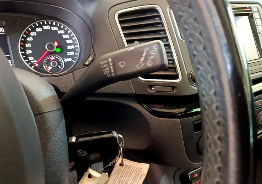 Gros plan intérieur sur le volant cuir et la commande d’essuie-glace du Volkswagen Sharan 2017, tableau de bord noir.