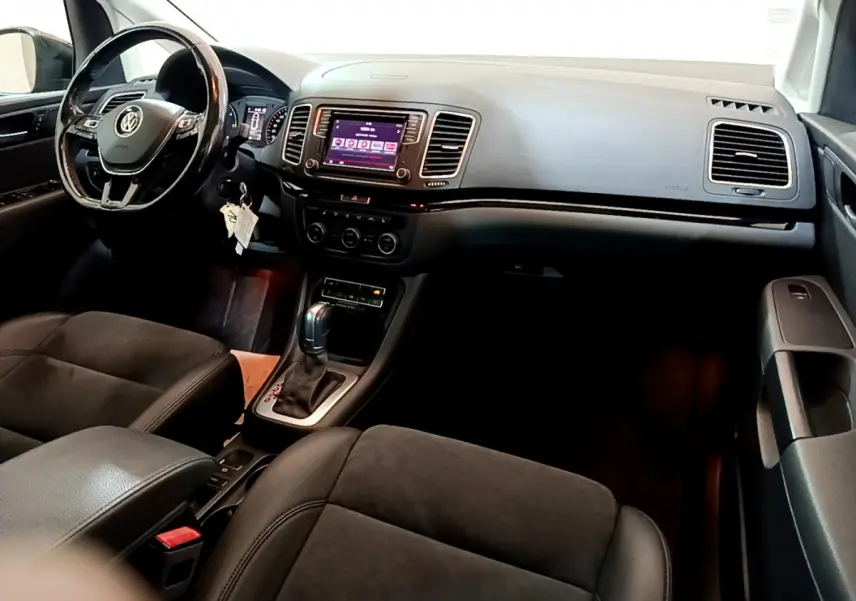 Intérieur noir du Volkswagen Sharan 2017 vu côté conducteur, avec tableau de bord et écran tactile central visible.