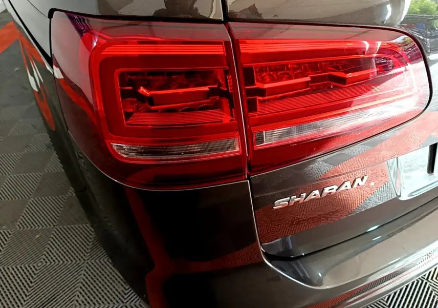 Gros plan sur le feu arrière gauche et le logo Sharan d'un Volkswagen Sharan marron 2017, vue arrière côté gauche.