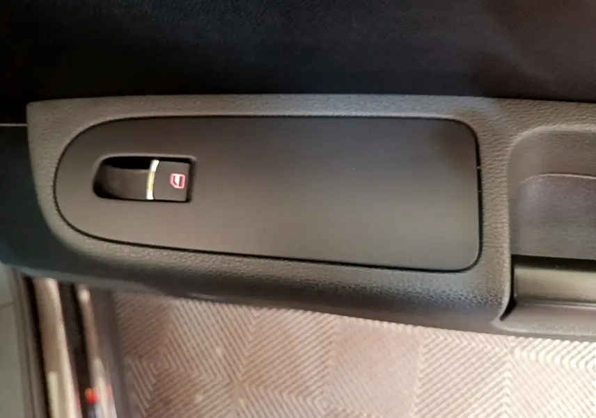 Gros plan sur le bouton de verrouillage des portes dans la portière intérieure d’un Volkswagen Sharan 2017 marron.