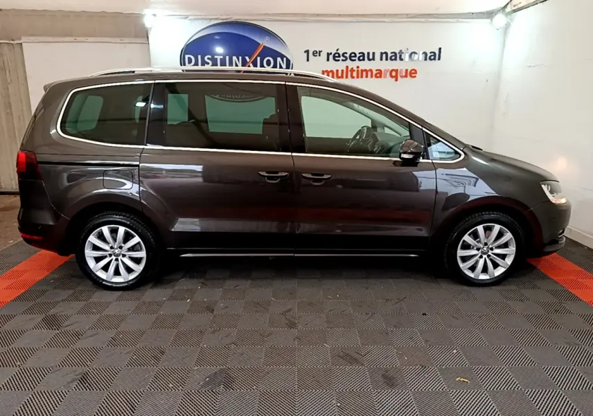 Profil droit d'un Volkswagen Sharan marron 2017 garé en intérieur sur sol carrelé noir et rouge.
