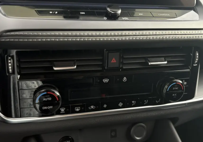 Gros plan sur la console centrale noire du Nissan Qashqai blanc nacré, montrant les commandes de climatisation automatique bi-zone.