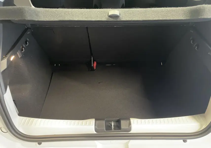 Vue du coffre ouvert d'une Dacia Sandero TCe 90 Stepway Expression blanc glacier, montrant l'espace de rangement intérieur.