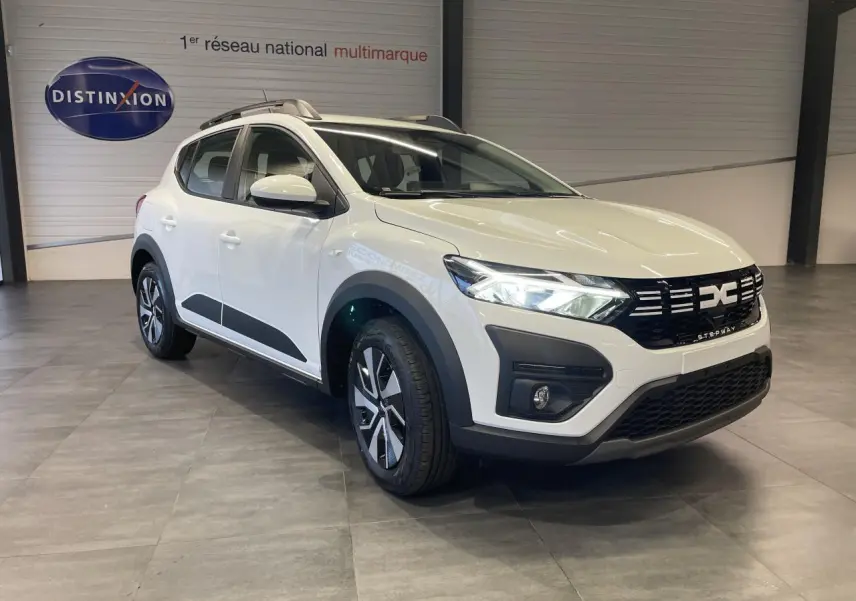 Vue 3/4 avant droite d'une Dacia Sandero Stepway blanche Glacier avec calandre noire et barres de toit grises.