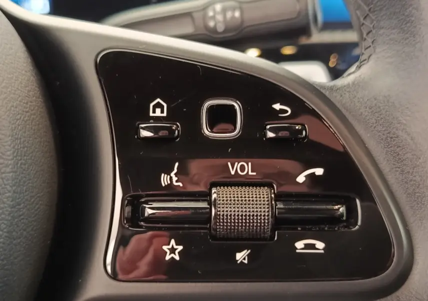 Gros plan sur les commandes noires du volant cuir multifonctions de la Mercedes Classe A 180 Business Line.