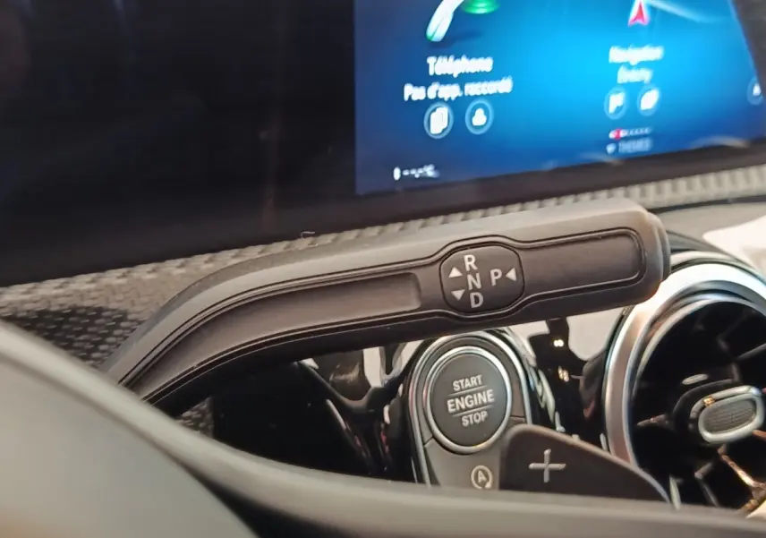 Gros plan sur la commande de boîte automatique et bouton start/stop du tableau de bord d'une Mercedes Classe A gris clair.