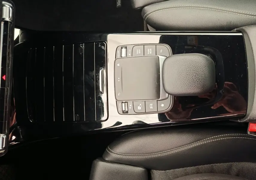 Vue plongeante sur la console centrale noire brillante de la Mercedes Classe A 180 Business Line avec levier de vitesses cuir.