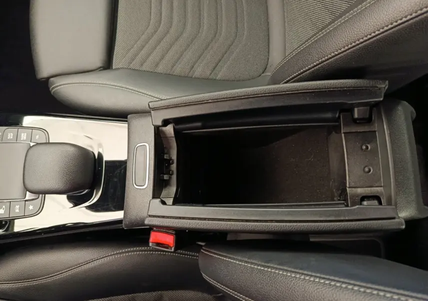 Vue intérieure en plongée du compartiment de rangement central noir et du levier de vitesse d'une Mercedes Classe A gris clair.