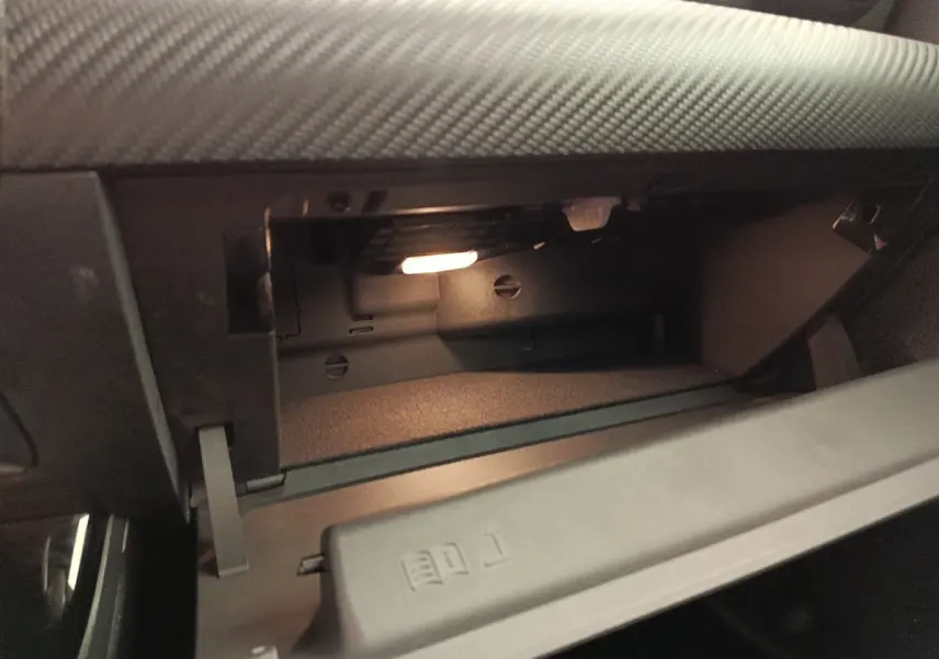 Gros plan sur la boîte à gants ouverte du Mercedes Classe A 180 Business Line gris clair, intérieur noir.